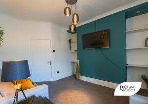 盖茨黑德Luke Stays - Brighton Road的客厅设有蓝色墙壁和电视。