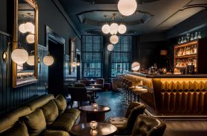 阿姆斯特丹阿姆斯特丹普利策酒店的酒吧配有皮革家具和吧台