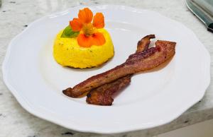 威诺纳Carriage House Bed & Breakfast的一小盘带培根和黄色 ⁇ 萝的食物
