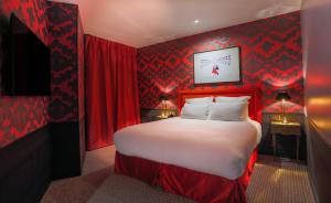 巴黎Hôtel La Parizienne的一间卧室设有一张带红色墙壁的大床