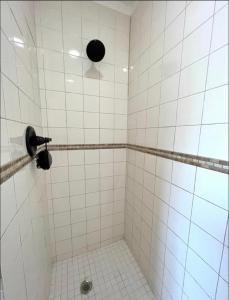 克利尔沃特Hostal Sky Crest的白色瓷砖浴室设有风扇和淋浴