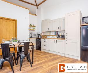 奥斯威斯ByEvo Oswestry Barn - Quirky romantic retreat or cosy contractor base的厨房配有白色橱柜和桌椅