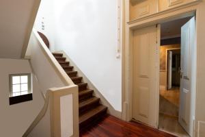 里斯本Rossio FLH Suites的房屋内的楼梯,拥有白色的墙壁和木地板