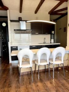 梅莱纳拉Bereli Beach的厨房配有桌子和四把白色椅子