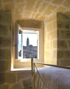 马泰拉卡萨维多利亚度假屋的一间卧室设有窗户,享有建筑的景色