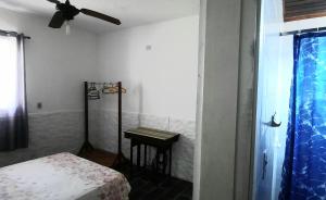 瓜鲁雅PousadaRecanto684Guarujá的一间卧室配有一张床、一张桌子和吊扇