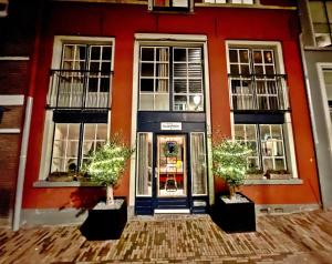迪温特Atelier Raamwerk City Apartments Deventer 125m2!的门前有两棵盆栽树的红色建筑