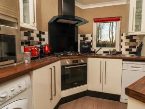 哈罗盖特Swinsty Lodge的厨房配有白色橱柜和炉灶烤箱。