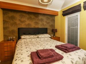 哈罗盖特Swinsty Lodge的一间卧室配有一张床,上面有两条毛巾