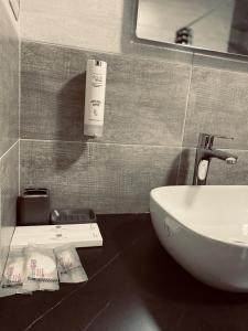 普里什蒂纳Hotel Callisto的浴室配有盥洗盆、镜子和盥洗盆