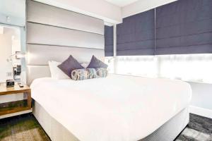 泰恩河畔纽卡斯尔Sandman Signature Newcastle Hotel的卧室配有带枕头的大型白色床