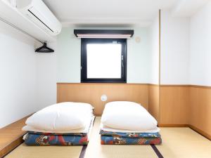 东京Chang Tee Hotel Ikebukuro的带窗户的客房内的两张床