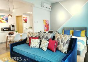 关丹Comfy Imperium Residence Kuantan Studio Seaview的客厅配有蓝色沙发及色彩缤纷的枕头