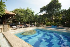 沙努尔罗摩衍那酒店的度假村的游泳池,有人坐