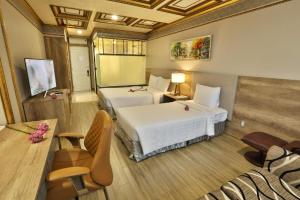 胡志明市Lotus Saigon Hotel的酒店客房带两张床和一张桌子以及椅子。