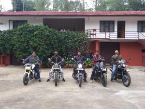GonikoppalShree Raksha Homestay的一群骑摩托车的人停在大楼前