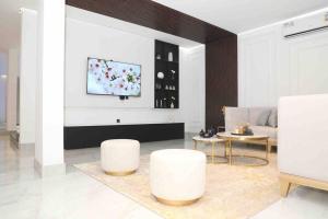 塞拉莱Cloud Villa Salalah的客厅配有2张白色凳子和电视