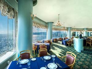 热海Hotel New Akao的餐厅设有蓝色的桌椅和窗户。