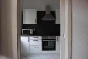 开姆尼茨alexxanders Apartments & Studios的厨房配有白色橱柜和微波炉