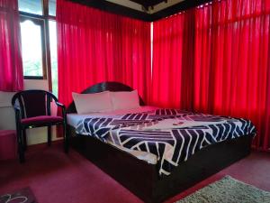 尼尔岛Hotel Highness Sea Rock的一间卧室配有红色窗帘、一张床和椅子