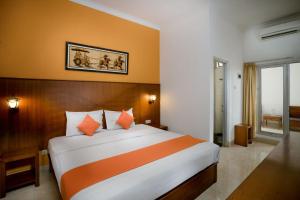 日惹Hotel Poncowinatan - Tugu的一间卧室配有一张带橙色和白色床单的大床