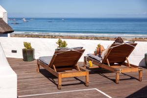 帕特诺斯特Abalone Hotel & Villa's的一位躺在沙滩上两把椅子上的女人