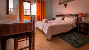 瓦尔扎扎特Hotel Rayyan l 'Escale的一间卧室配有一张大床、一张书桌和一个窗户。