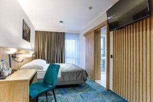 沃姆扎格罗马达沃姆扎酒店的酒店客房配有一张床、一张书桌和一台电视。