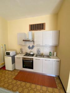 Ronco CanaveseLo Bec的厨房配有白色橱柜和炉灶烤箱。