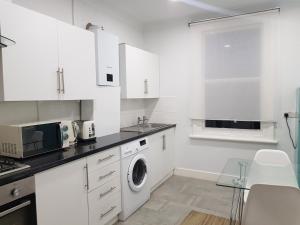 伦敦London. Gorgeous 2 bed flat near Olympic Park.的白色的厨房配有洗衣机
