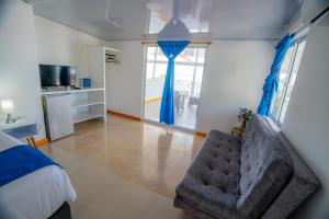 普罗维登西亚Hotel El Pirata Morgan的一间卧室配有沙发和一张带蓝色窗帘的床