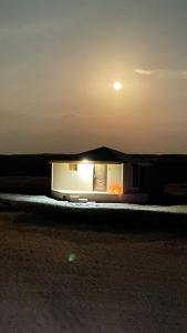 ḨawīyahSafari Dunes Camp的一座小建筑,晚上有月亮在天空中