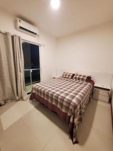 卡马萨里Village de Praia Duplex Arembepe的一间卧室配有一张带铺着地毯的床和窗户。