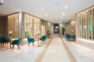 埃格尔Allure Healthy Hotel & Spa的一间设有绿色椅子和桌子的等候室