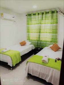 CiénagaHotel Don Jose的客房设有两张带绿床单的床和窗户。