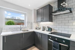 格兰奇茅斯Grangemouth, 3 Bed House, Free Parking, Business or Leisure的厨房配有灰色橱柜、水槽和窗户。