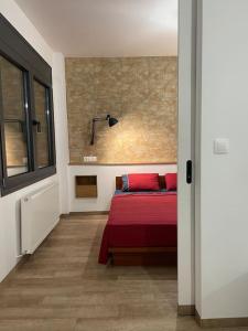 亚历山德鲁波利斯Central cozy apartment with garden的一间卧室配有一张带红色床单的床和一扇窗户。
