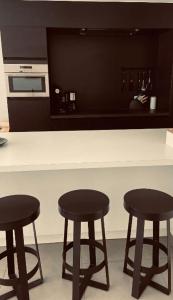 尼乌波特Dolce Vita - zonnig familie appartement met garagebox的厨房在柜台上设有三个黑吧台凳