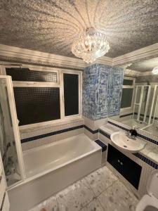莱斯里普TJ Homes - Double room with Single Bed - 3 Min to Tube station - London的带浴缸、水槽和吊灯的浴室