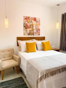 凯鲁Villa do Mar的一间卧室配有一张带黄色枕头和椅子的床