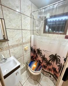 南圣弗朗西斯科Pousada Happy的浴室设有卫生间和棕榈树淋浴帘