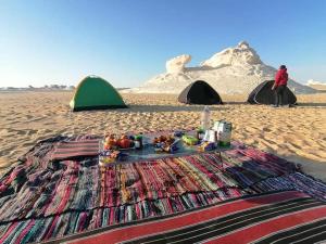 BawatiWestern desert safari的沙滩上铺着毯子,沙滩上还摆放着帐篷