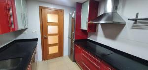 休达Gran piso cerca Centro Comercial y Playa的厨房配有红色橱柜和黑色台面