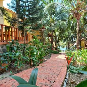 富国Viet Thanh Resort的棕榈树建筑前的砖砌走道