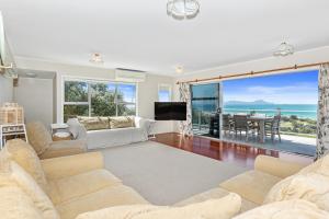 怀普Surfers Lookout - Waipu Cove Holiday Home的带沙发、电视和桌子的客厅