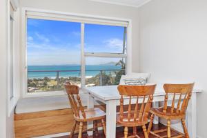 怀普Surfers Lookout - Waipu Cove Holiday Home的一间带桌椅和窗户的用餐室