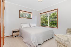 怀普Surfers Lookout - Waipu Cove Holiday Home的白色的卧室设有床和窗户