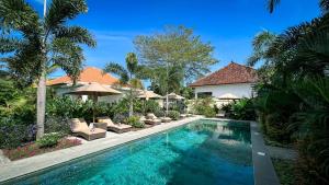 塞隆贝拉纳克Green Valley Lombok的房屋旁的游泳池配有椅子和遮阳伞