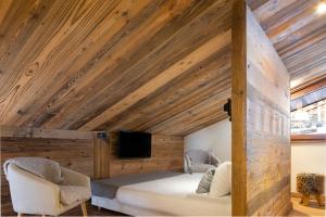 大博尔南Hôtel et Spa Le Vermont的一间卧室设有木制天花板、一张床和两把椅子
