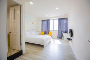 台南Key We Go Hotel 奇遇果文旅的卧室配有白色的床和黄色椅子